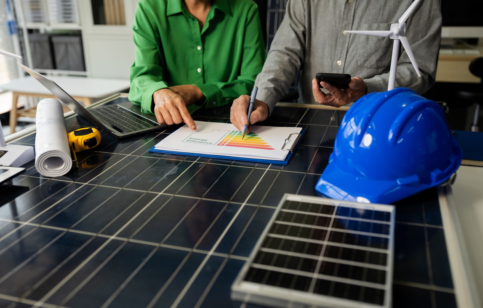 Two colleagues discussing data working and tablet, laptop with on Construction Site project, green energy and solar panel concept.