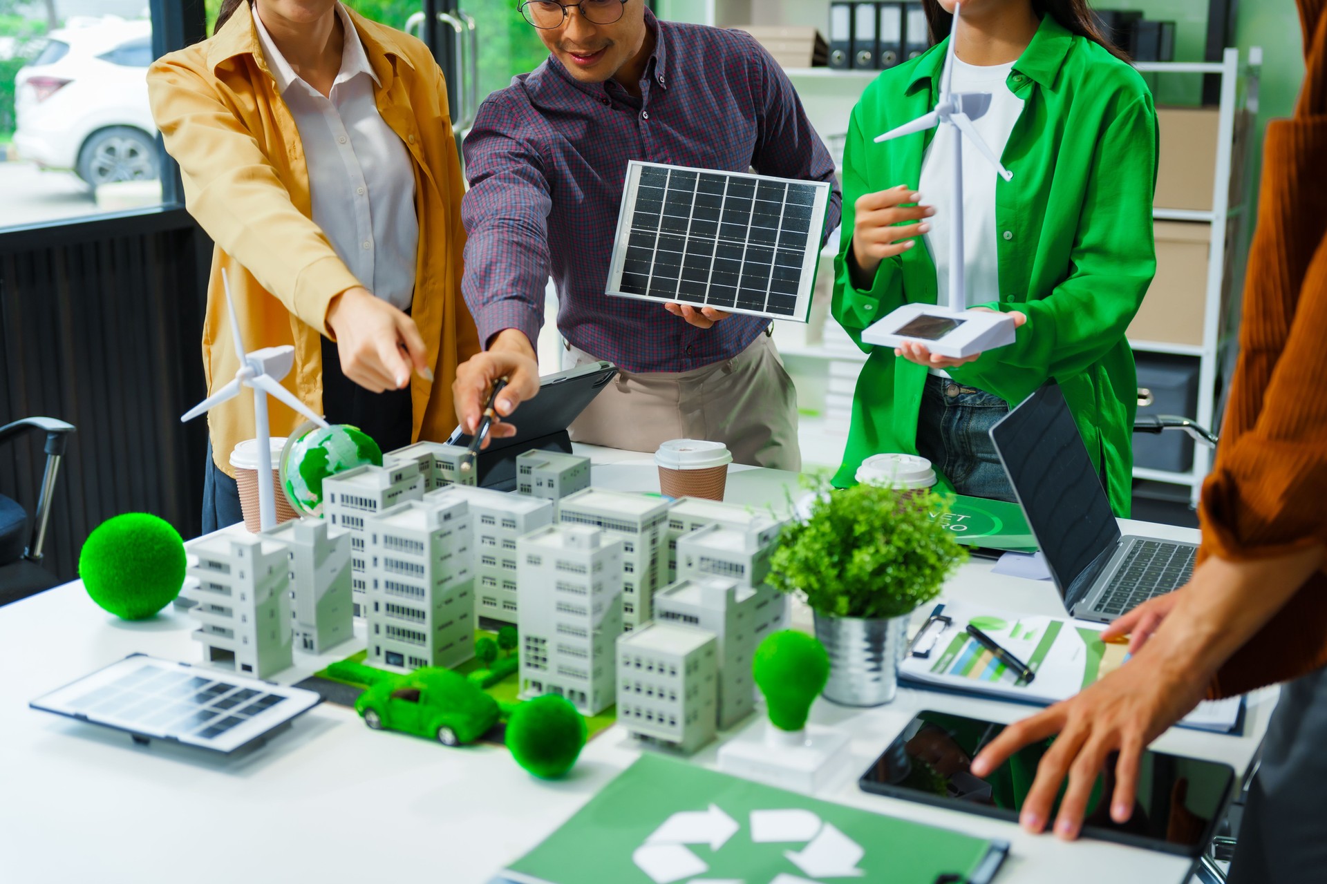 Colleagues in formal suits meet at desk to brainstorm environmental management strategies. discuss carbon emissions, renewable energy, sustainable business practices to reduce corporate footprint.